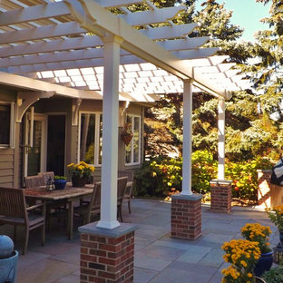 Cette image montre une terrasse arrière craftsman de taille moyenne avec des pavés en pierre naturelle et une pergola.