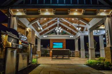 Modelo de patio de estilo americano grande en patio trasero con chimenea, adoquines de piedra natural y cenador