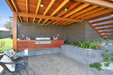 Diseño de patio moderno en patio trasero con cocina exterior y losas de hormigón