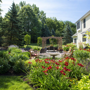 Example of a large classic backyard stone patio fountain design in Milwaukee with a pergola