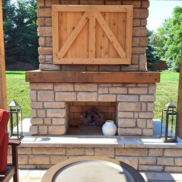 Farmhouse outdoor fireplace with custom cedar tv cabinet