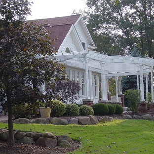 Foto di un grande patio o portico country davanti casa con pavimentazioni in mattoni e una pergola