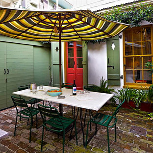 Foto di un patio o portico eclettico in cortile con pavimentazioni in mattoni e un parasole