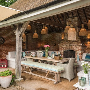 Foto di un patio o portico bohémian dietro casa con un tetto a sbalzo e un caminetto