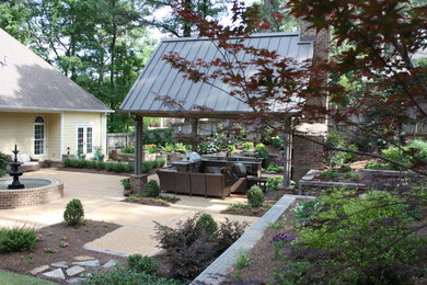 Cette image montre une terrasse arrière traditionnelle avec un foyer extérieur, des pavés en brique et une pergola.