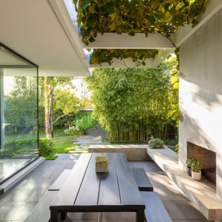 This is an example of a mid-sized contemporary backyard patio in Melbourne with with fireplace, natural stone pavers and a pergola.