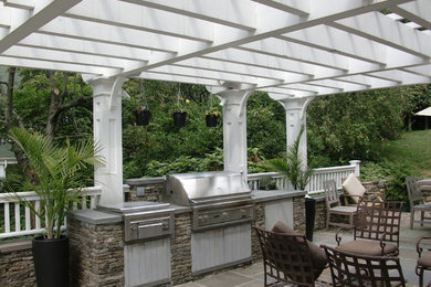 Example of a mid-sized minimalist backyard stone patio kitchen design in New York with a pergola