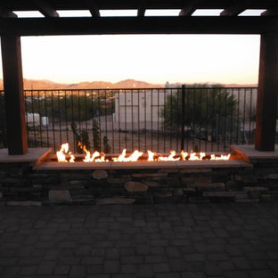 Ispirazione per un patio o portico etnico di medie dimensioni e dietro casa con un focolare, pavimentazioni in mattoni e una pergola