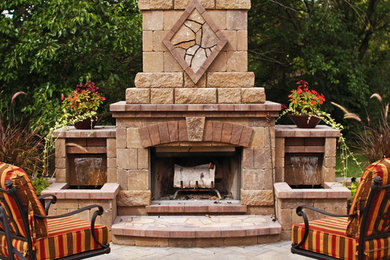 Example of a tuscan stone patio design in Other with a fireplace and no cover