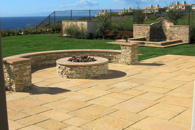Photo of a large classic back patio in Los Angeles with a fire feature, natural stone paving and no cover.