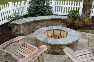 Example of a mid-sized arts and crafts backyard stone patio design in New York with a fire pit and no cover