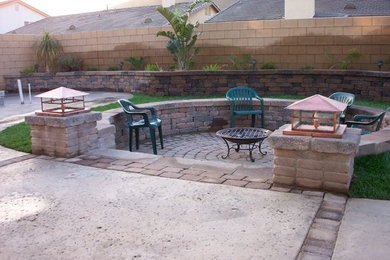 This is an example of a medium sized traditional back patio in Los Angeles with a fire feature, brick paving and no cover.