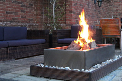 Photo of a medium sized contemporary back patio in London with a fire feature.