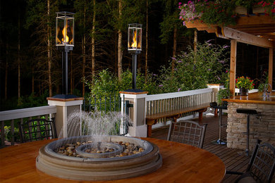 Patio fountain - large traditional backyard patio fountain idea in Boston with decking and a pergola