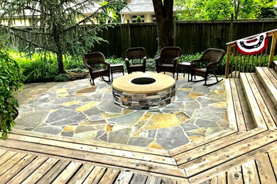 Example of a mid-sized trendy backyard stone patio design in Kansas City with a fire pit and no cover