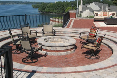 Inspiration for a large contemporary backyard brick patio remodel in Other with a fire pit and no cover