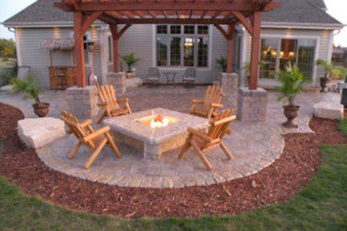 Inspiration for a backyard brick patio remodel in Milwaukee with a fire pit and a pergola