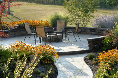 Example of a backyard concrete paver patio design in Grand Rapids with a fire pit and no cover