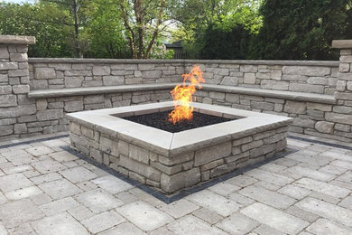 Patio - large traditional backyard stone patio idea in Chicago with a fire pit and no cover