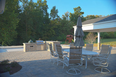 Idées déco pour une très grande terrasse arrière avec une cuisine d'été, des pavés en béton et une extension de toiture.