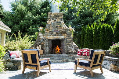 Large mountain style backyard stone patio photo in New York with a fire pit and no cover