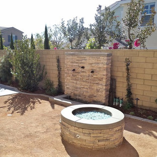Idee per un patio o portico mediterraneo dietro casa con un focolare e graniglia di granito