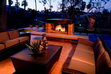This is an example of a large contemporary back patio in Los Angeles with a fire feature, tiled flooring and a roof extension.