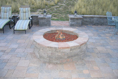 Example of a mid-sized backyard stone patio design in Denver with a fire pit and no cover