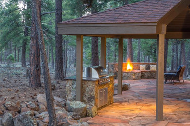 Large mountain style backyard stone patio kitchen photo in Phoenix with a roof extension