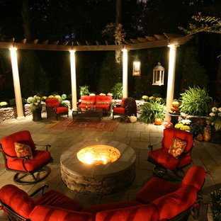 Example of a mid-sized classic backyard stone patio design in DC Metro with a fire pit and a pergola