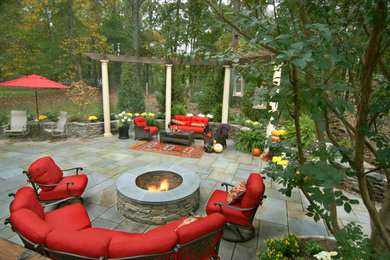 Ejemplo de patio tradicional de tamaño medio en patio trasero con brasero, adoquines de piedra natural y pérgola