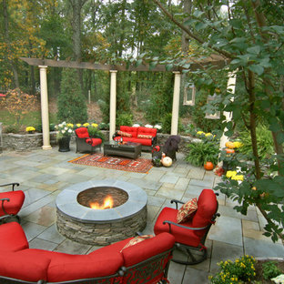 Example of a mid-sized classic backyard stone patio design in DC Metro with a fire pit and a pergola