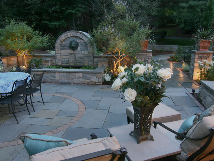 An illustration of a sizable traditional backyard stone patio fountain design