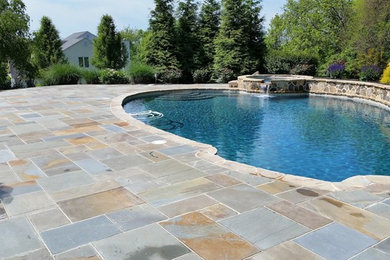 Diseño de piscina de estilo de casa de campo grande en patio trasero con adoquines de piedra natural