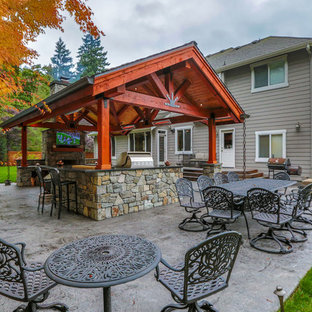 Immagine di un grande patio o portico american style dietro casa con lastre di cemento e un tetto a sbalzo