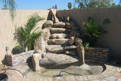Patio fountain - mid-sized backyard stone patio fountain idea in Phoenix with no cover