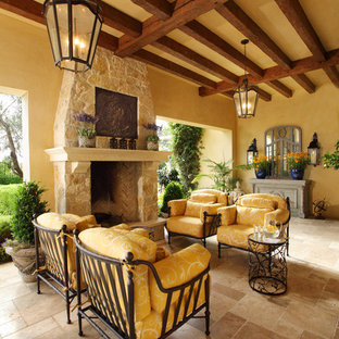 Idee per un patio o portico mediterraneo con piastrelle, un tetto a sbalzo e un caminetto