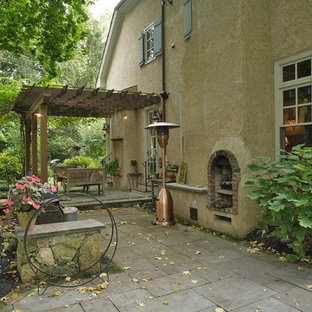 Foto di un patio o portico classico dietro casa e di medie dimensioni con un focolare, pavimentazioni in cemento e una pergola