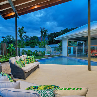 Idee per un grande patio o portico tropicale dietro casa con piastrelle e un gazebo o capanno