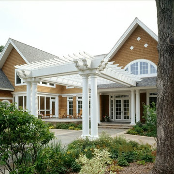 Front view of home from garden with pergola over drive