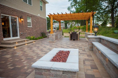 Diseño de patio clásico de tamaño medio en patio trasero con brasero, adoquines de ladrillo y pérgola