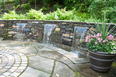 Small rustic back patio in Montreal with a water feature, natural stone paving and no cover.