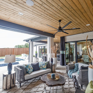 Immagine di un grande patio o portico eclettico dietro casa con pavimentazioni in cemento e un tetto a sbalzo