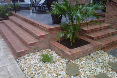 Example of a mid-sized backyard brick patio design in Other with no cover
