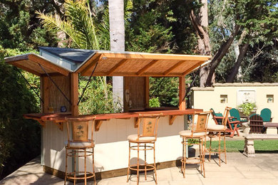 Patio kitchen - mid-sized tropical backyard concrete paver patio kitchen idea in Santa Barbara with an awning