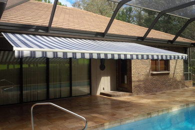 Photo of a back patio in Tampa with a water feature, tiled flooring and an awning.