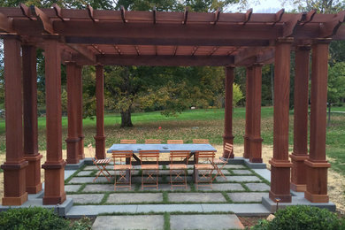 Inspiration for a large backyard stone patio remodel in New York with an awning
