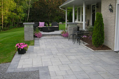 Large elegant front yard stone patio photo in Toronto with a roof extension