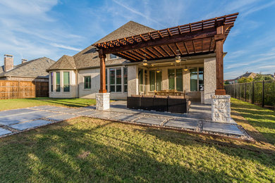Large classic back patio in Dallas with an outdoor kitchen, stamped concrete and a pergola.