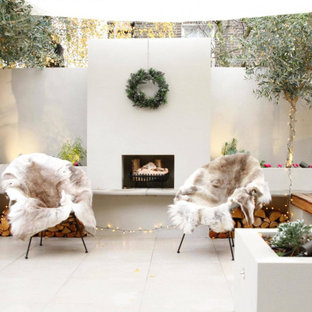 Photo of a contemporary back patio in London with a fireplace, tiled flooring and no cover.